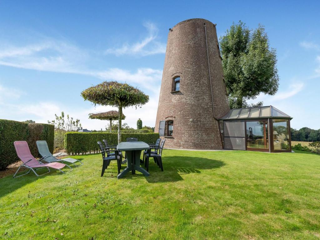 a building with a table and chairs in the grass at Charming Oombergen Mill Retreat in Zottegem