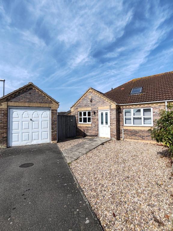 a brick house with white garage doors and a driveway at Deja Blue in Sutton on Sea