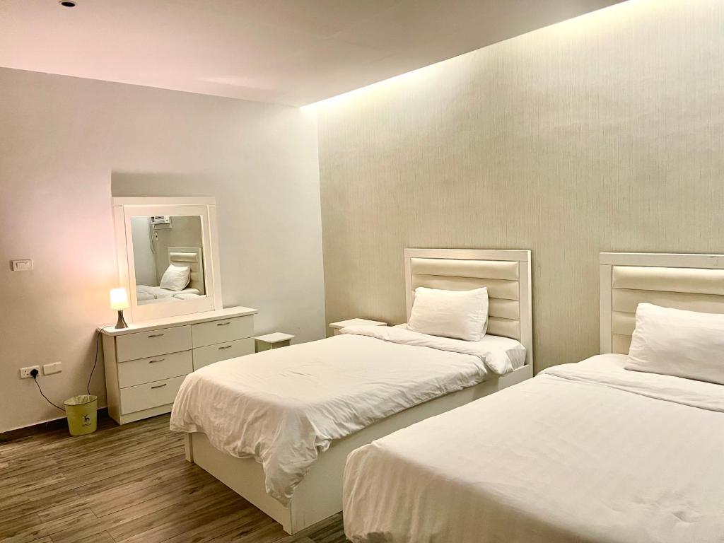a bedroom with two beds and a mirror at شقة ثلاث غرف in Al-Safa