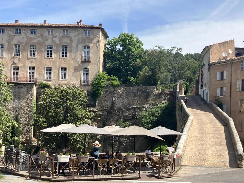 people sitting at tables with umbrellas in front of a building at La tourelle aux hirondelles in Entrecasteaux