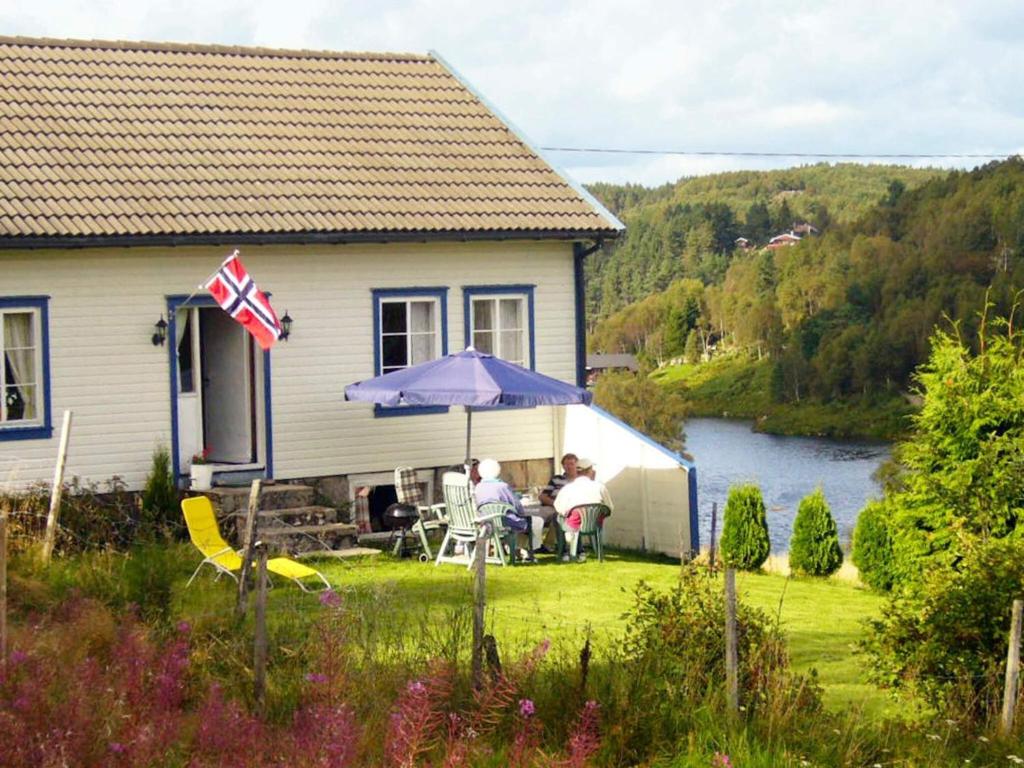 two people sitting under an umbrella in the yard of a house at 6 person holiday home in lyngdal-By Traum in Lyngdal