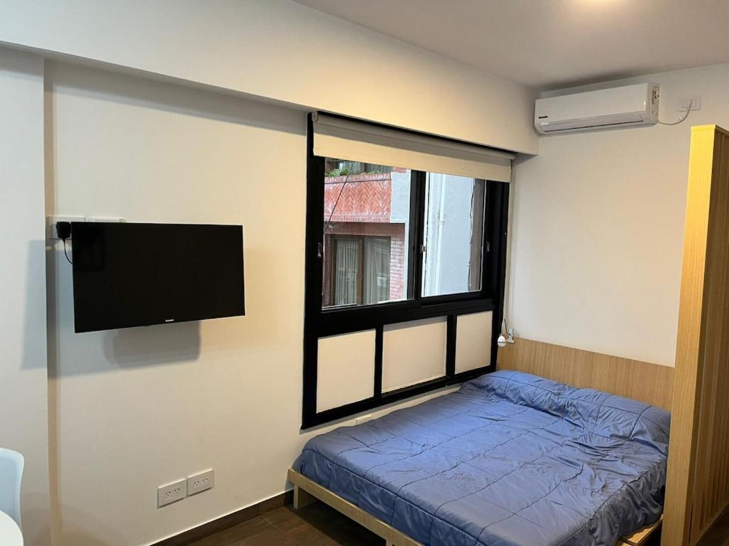 a bedroom with a bed and a flat screen tv at Apartment equipped with amenities ideal for two in Buenos Aires