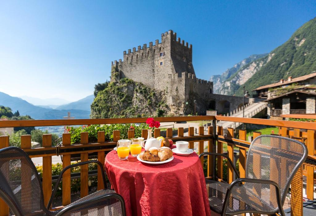 einen Tisch mit einem Teller Essen und ein Schloss in der Unterkunft Hotel Antica Croce - Gardaslowemotion in Tenno