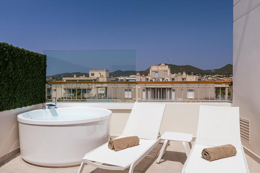 a balcony with a bath tub and two white chairs at Malacosta Sky Suites - MC Apartments Ibiza in Ibiza Town