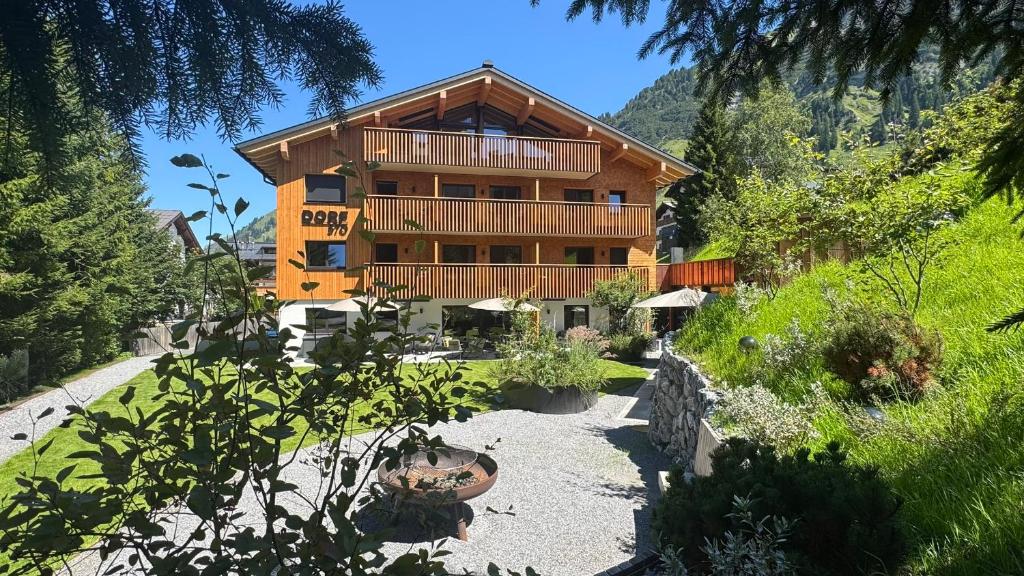 a large wooden house with a balcony on a hill at Aparthotel Dorf570 in Lech am Arlberg