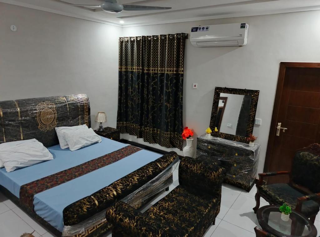 een slaapkamer met een bed, een spiegel en een stoel bij Ryazm Guest house in Rawalpindi