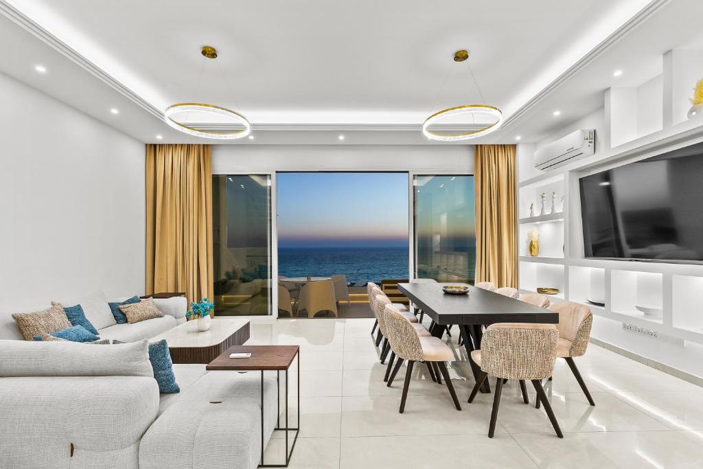 a living room with a couch and a table with chairs at Olymp White Palace - The Ultra Luxury Beachfront House in Kissonerga
