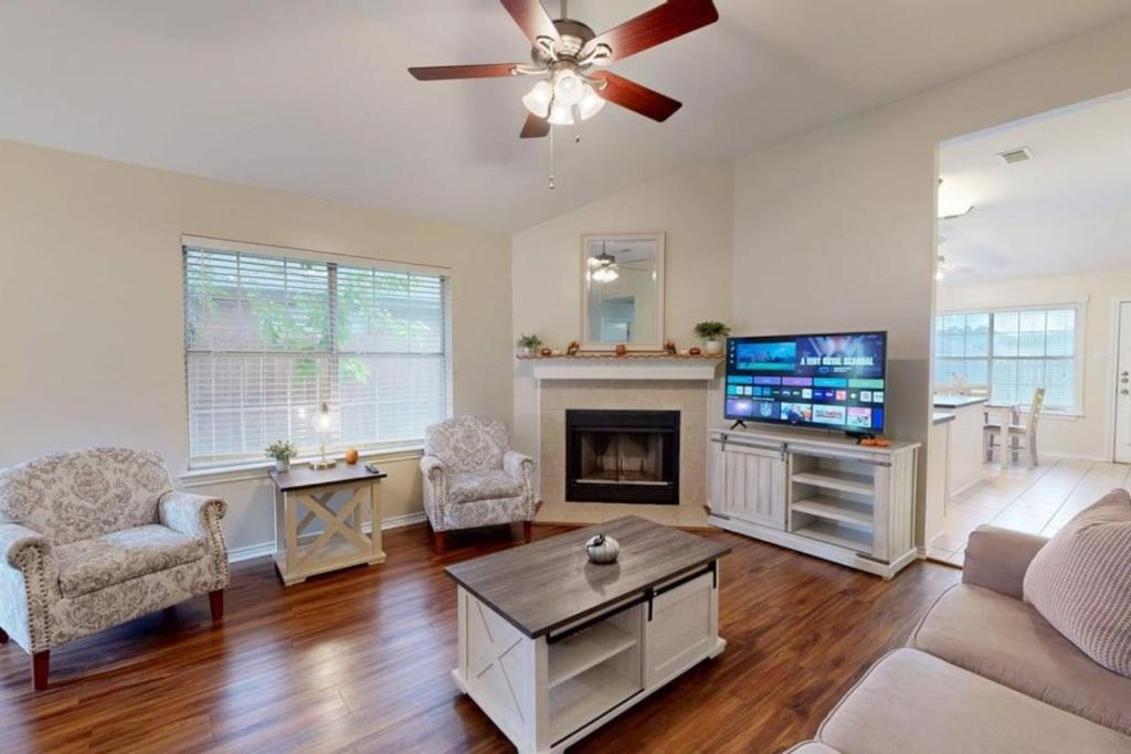 a living room with a ceiling fan and a tv at Camellia by Wolf Pen in College Station