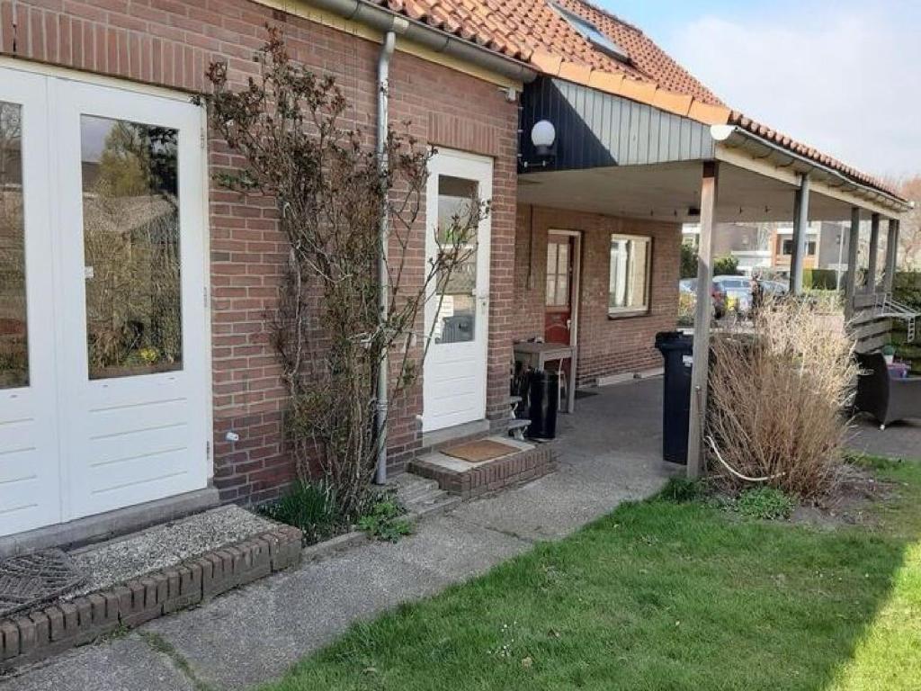 a brick house with white doors and a porch at Holiday Home Groet near Schoorl Dunes in Groet