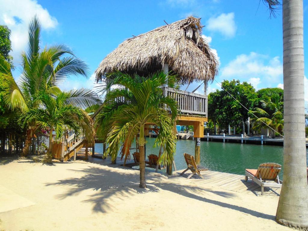 a hut on a beach next to a body of water at Dolce Cabana Waterfront Suites in Placencia