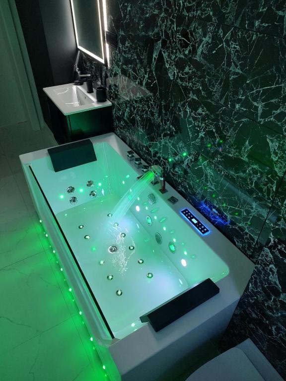 a bathroom with a sink and a tub with green lights at Cozy Calming Apartment in Poznań