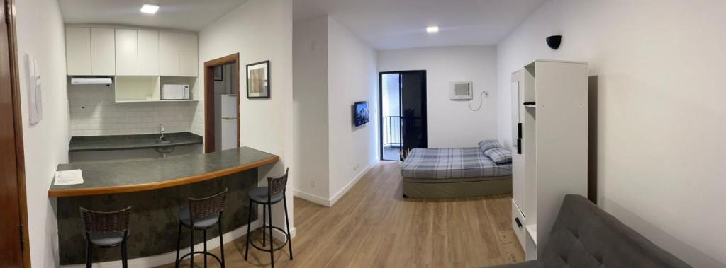 a kitchen with a bar and a room with a bed at Flat perto da praia com piscina na cobertura in São Vicente