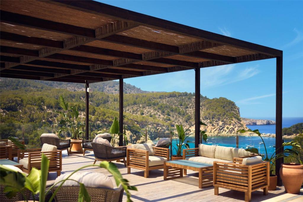 a patio with furniture and a view of the ocean at Cala San Miguel Ibiza Resort, Adults only, Curio Collection by Hilton in Puerto de San Miguel
