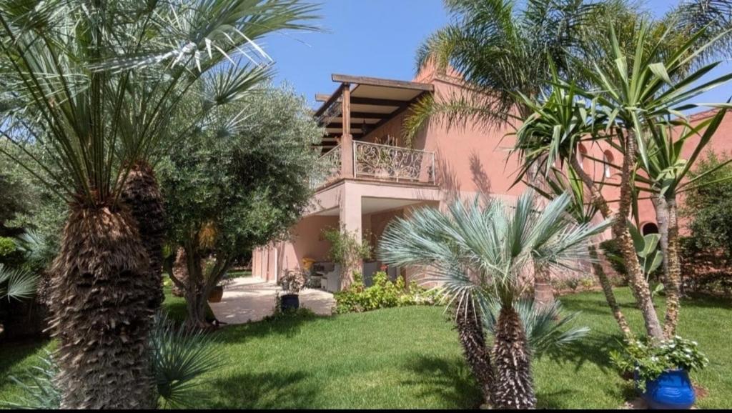 a pink house with palm trees in front of it at Charmante maison avec jardin et piscine in Marrakech
