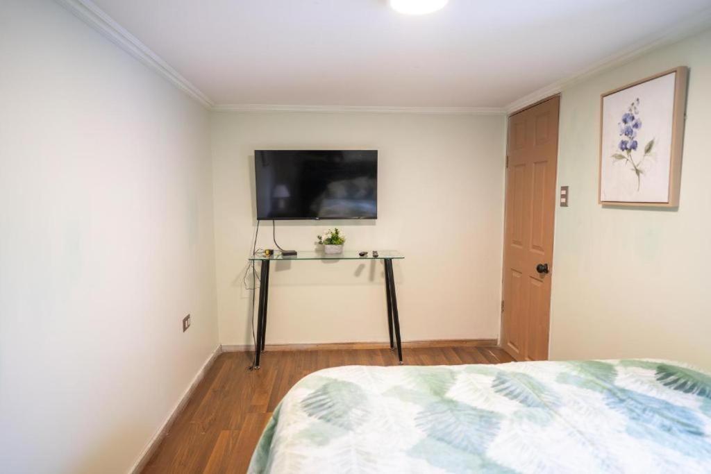 a bedroom with a bed and a tv on the wall at lindisimo casona hostal en el centro de santiago in Santiago
