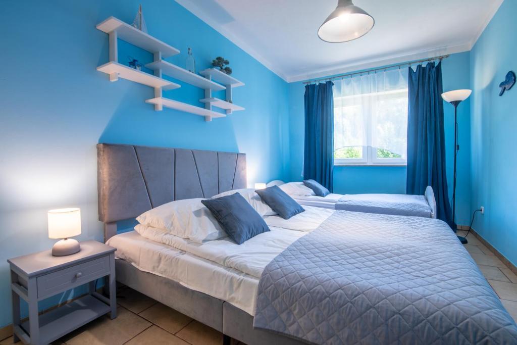 - une chambre bleue avec un grand lit aux murs bleus dans l'établissement Apartament Nostalgia, à Gąski