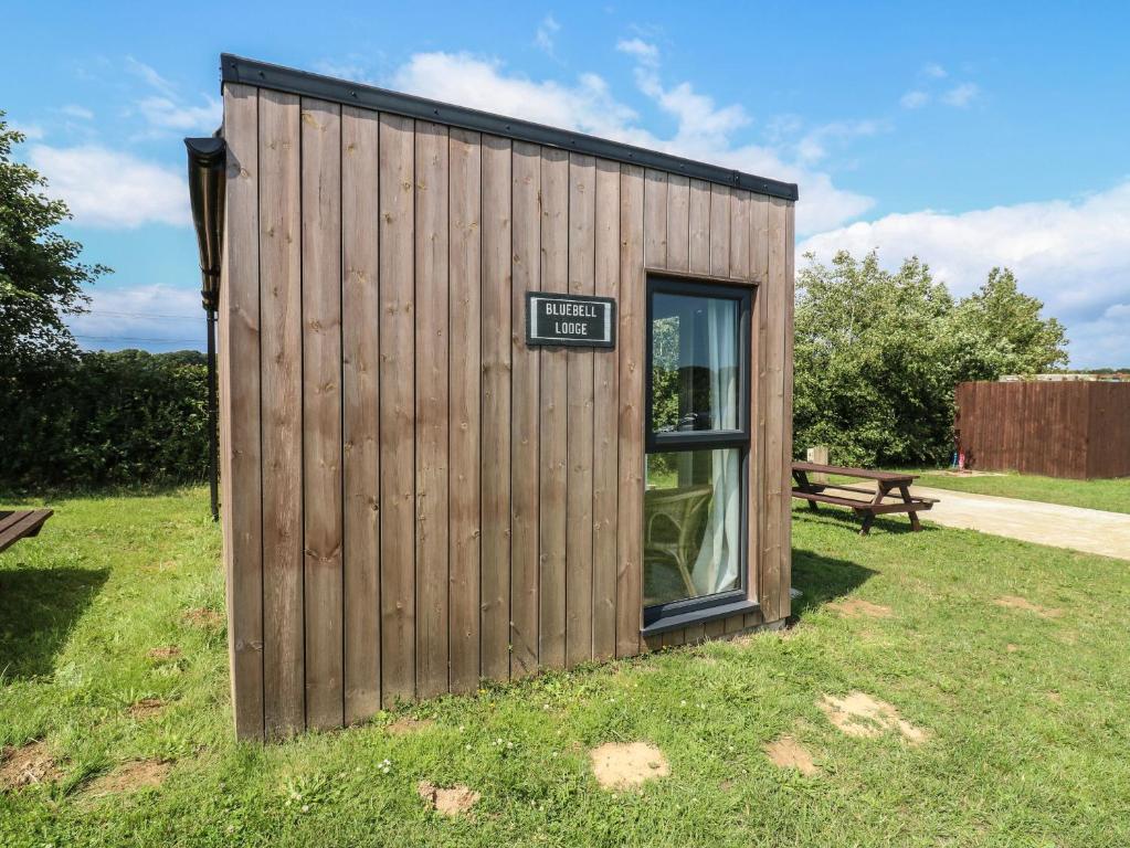 a small wooden building with a sign on the door at Bluebell Lodge in Battle