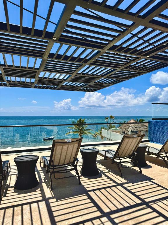 a patio with chairs and a view of the ocean at Bright Ocean View Studio with Rooftop Pool Access in Puerto Morelos