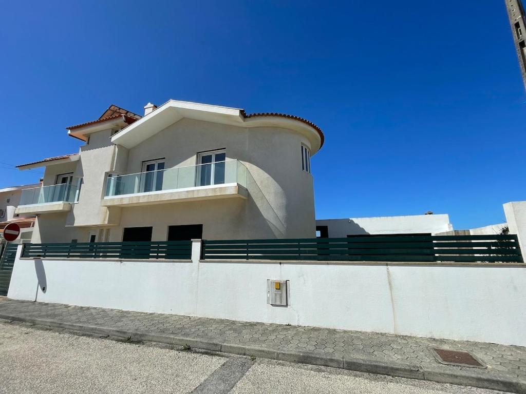 een groot wit huis met een groene leuning aan de zijkant bij Beachfront Costa Nova Villa - 2BR Apartment in Gafanha da Encarnação