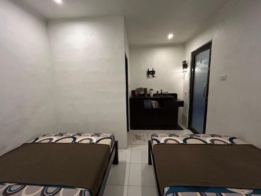 deux lits assis dans une pièce avec une fenêtre dans l'établissement Pasuruan heritage guest house, 