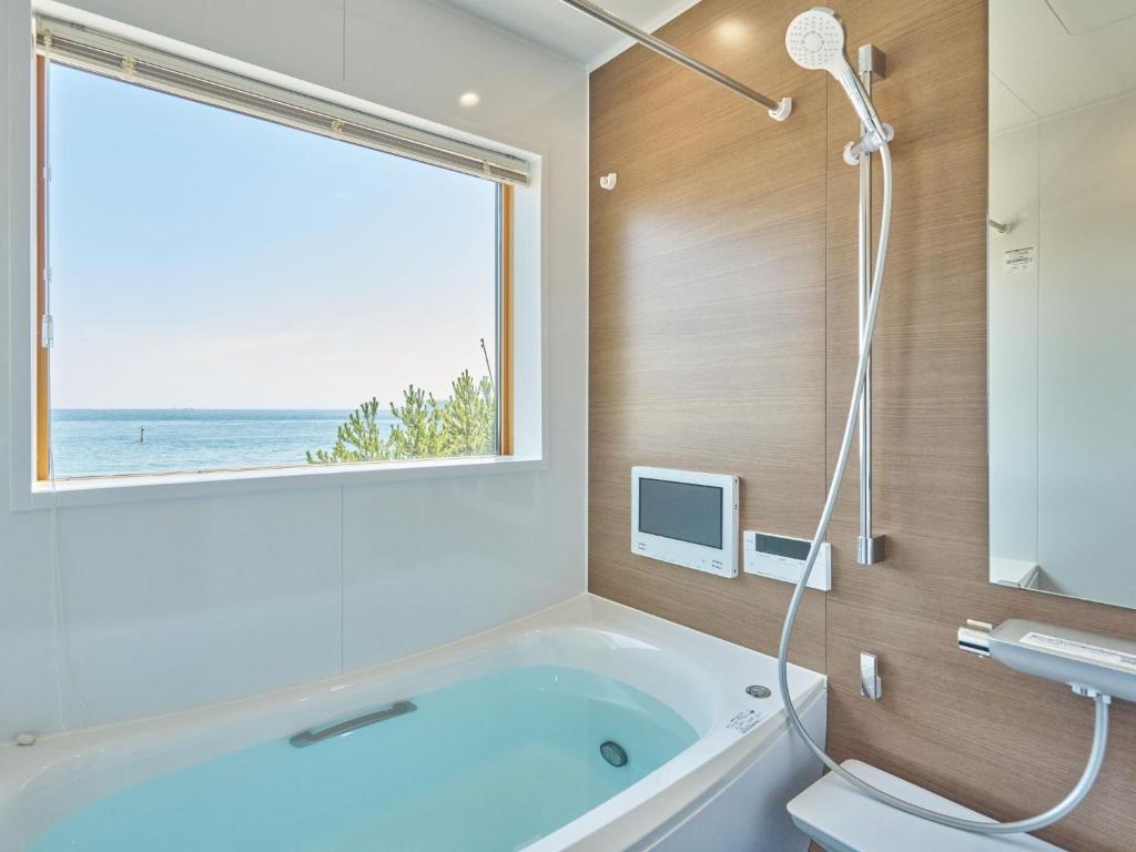 Un baño con bañera y ventana. en T,square - Vacation STAY 11435v, en Awaji