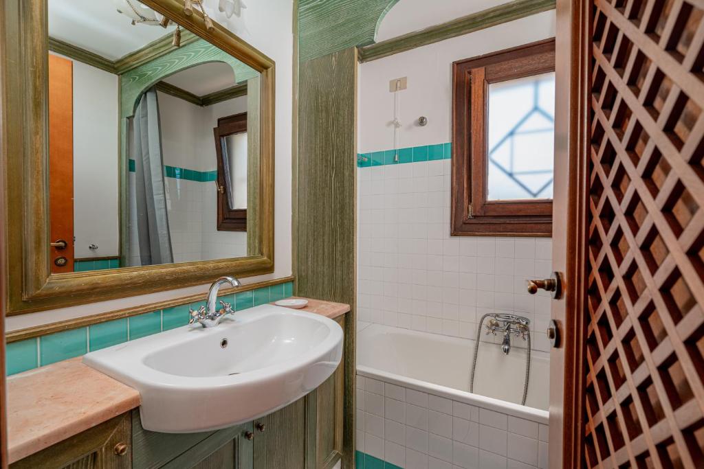 un bagno con un lavandino, una vasca e uno specchio di Cala del Faro - Giardino e accesso privato al mare a Arzachena