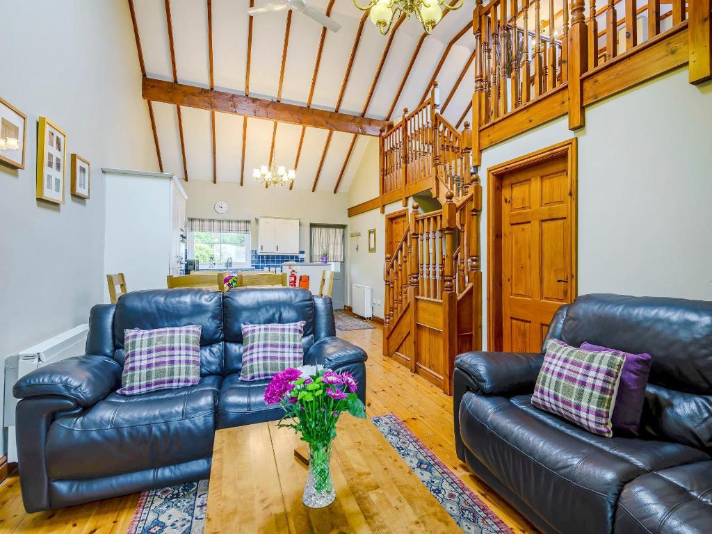 a living room with two leather couches and a table at Beudy - Uk31388 in Caeathro