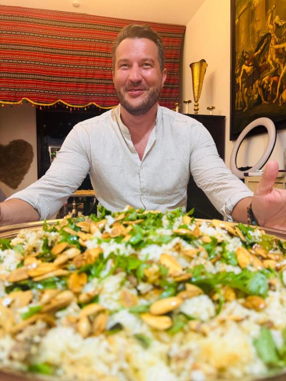 un hombre sentado frente a una pizza en dreams stay, en Dubái