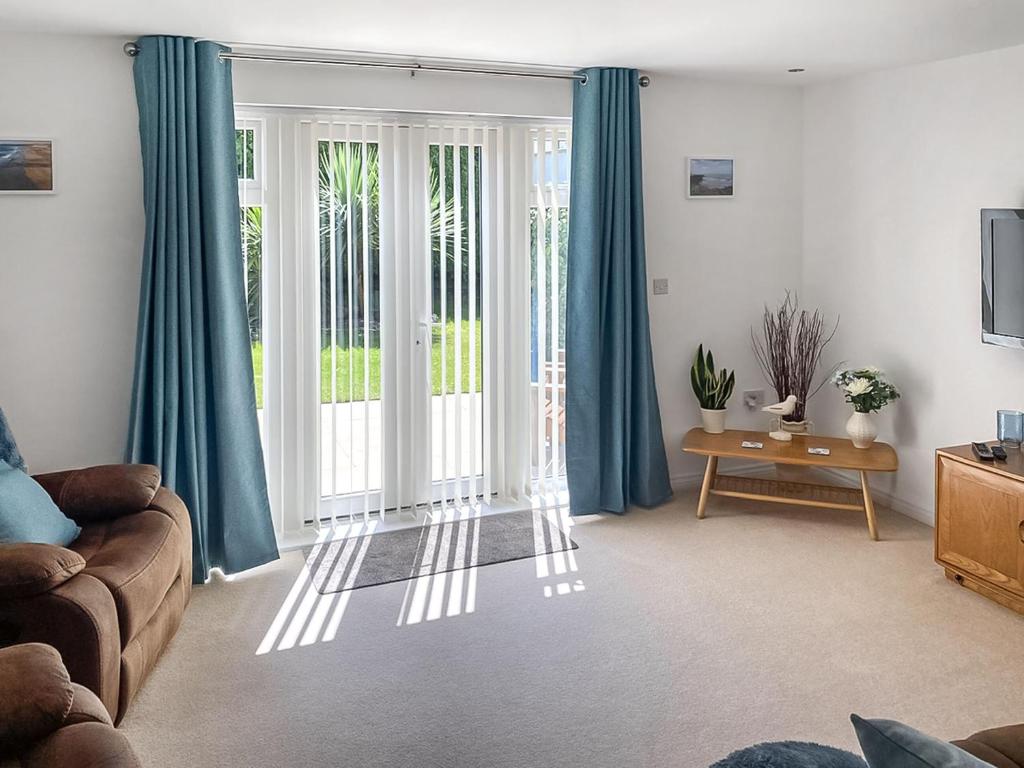 a living room with a couch and a sliding glass door at Blissful Ocean Breeze in Perranporth