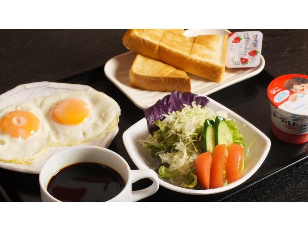a table with two plates of breakfast foods and a cup of coffee at Smile Hotel Nagoya Shinkansenguchi - Vacation STAY 05079v in Nagoya