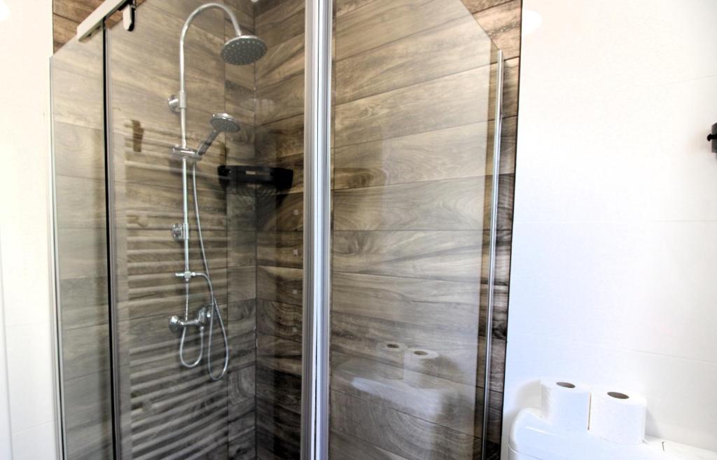 a shower in a bathroom with wooden walls at Pompa Apartman in Nyíregyháza