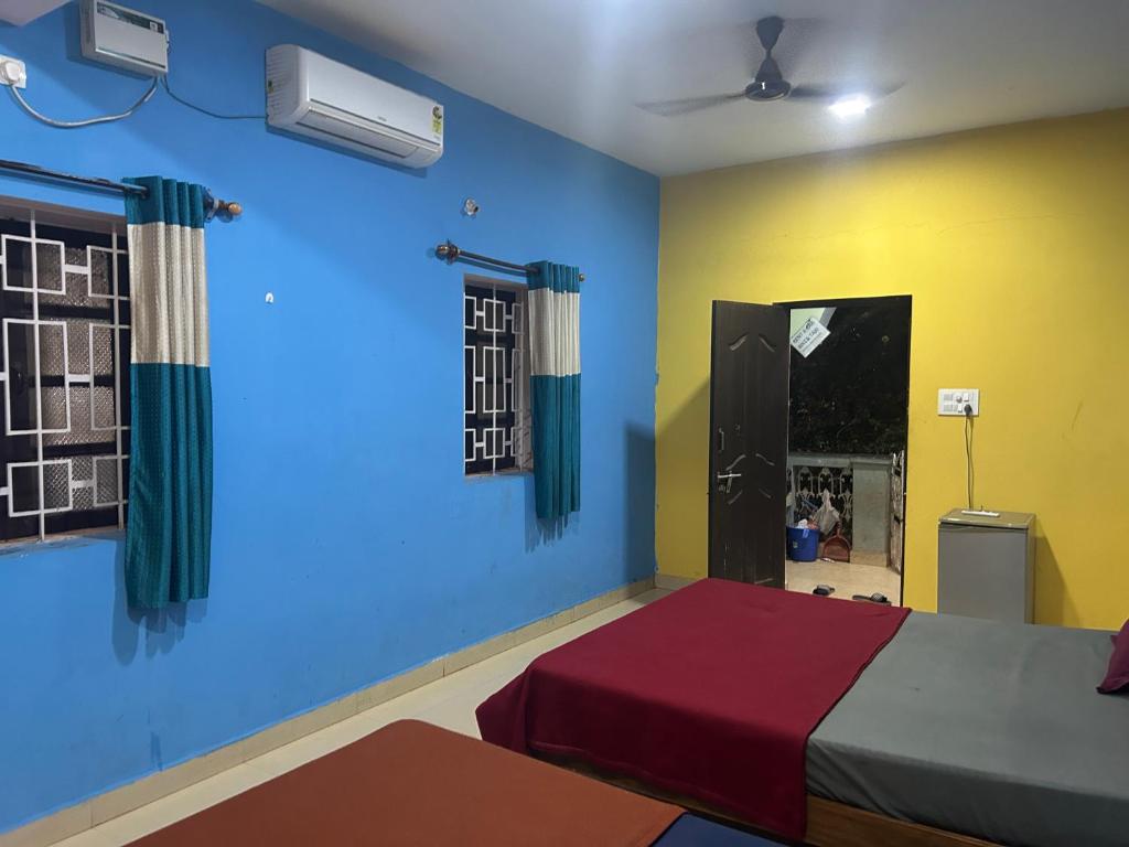 a bedroom with two beds and a blue wall at Pihu Hotel in Calangute