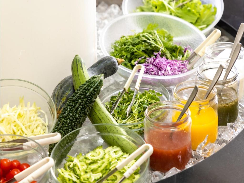 a table topped with bowls of vegetables and drinks at Smile Hotel Naha City Resort - Vacation STAY 05994v in Naha