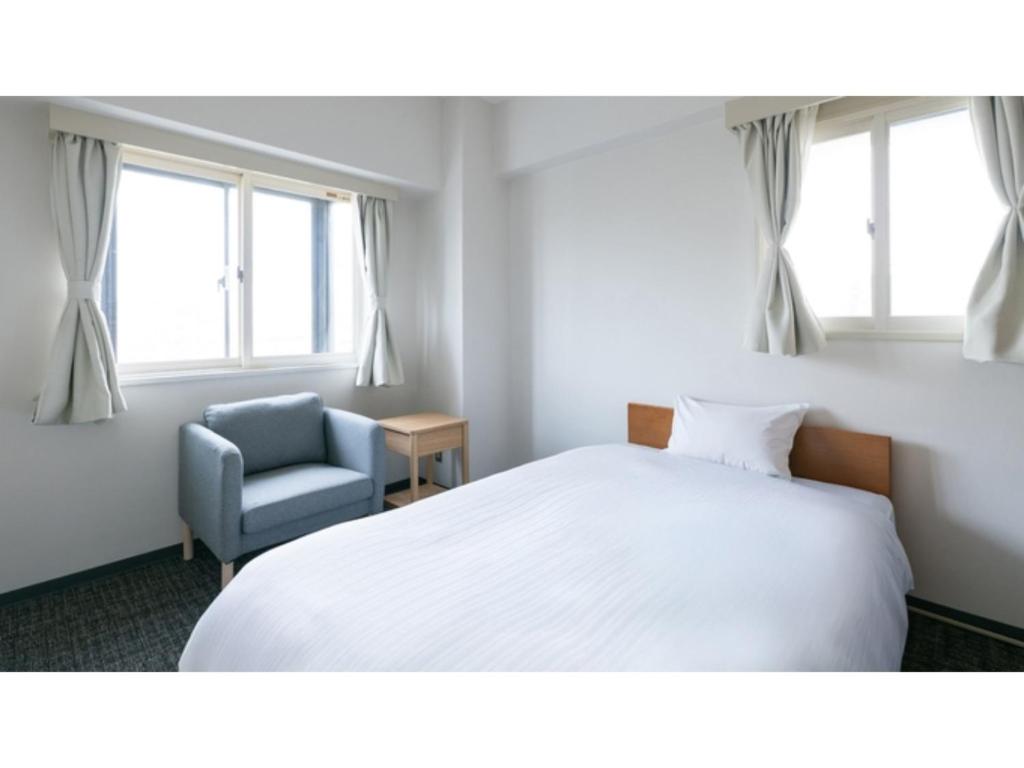 a bedroom with a bed and a blue chair at DIG the Osaka - Vacation STAY 96986v in Suita