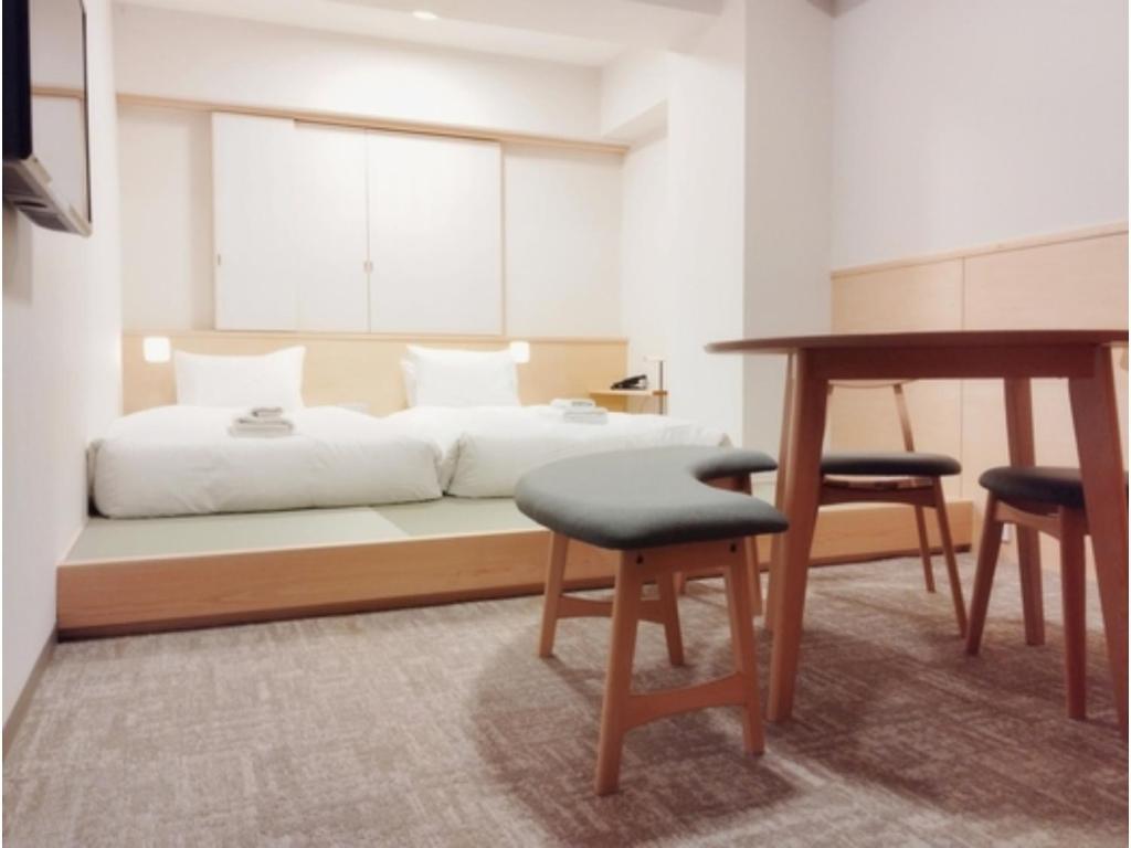 a bedroom with a bed with a desk and two chairs at DIG the Osaka - Vacation STAY 96973v in Suita