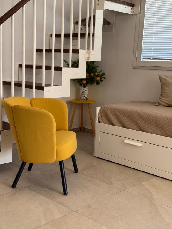 a bedroom with a yellow chair next to a bed at Casa MaLù in Aci Bonaccorsi