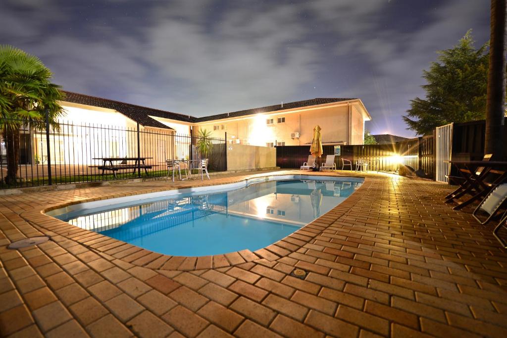 una piscina en un patio trasero por la noche en Winning Post Motor Inn, en Mudgee