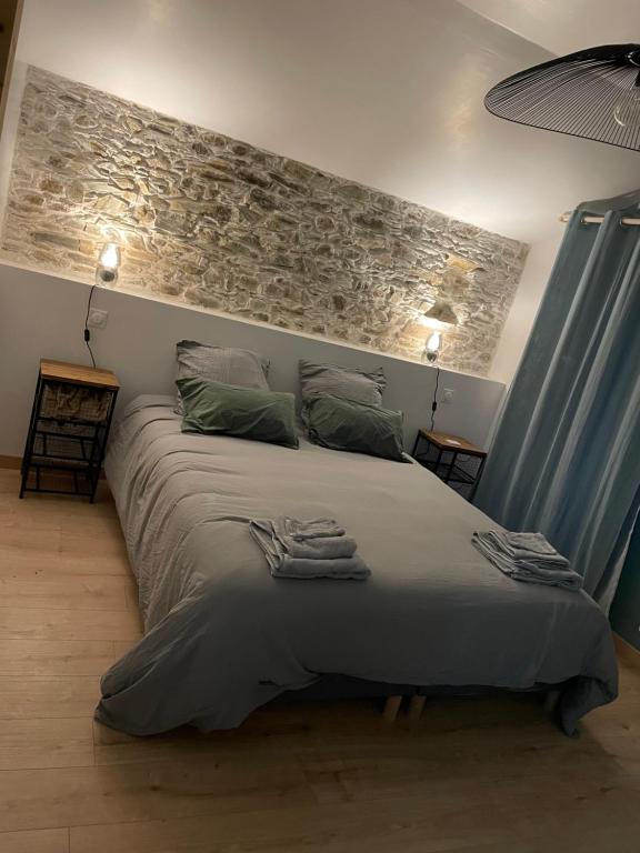 Un dormitorio con una cama grande con una pared de piedra. en La Grange maen, en Pont-Saint-Martin