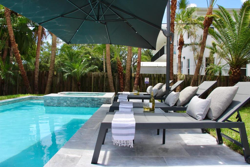 a pool with chairs and an umbrella next to a swimming pool at Fox Private Resort- Near Downtown & Beach in Fort Lauderdale