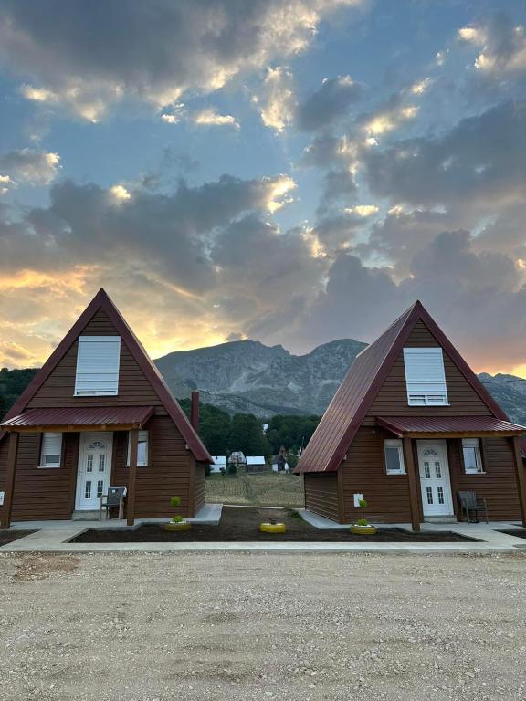 two wooden homes with mountains in the background at Etno Villa Popovic in Žabljak