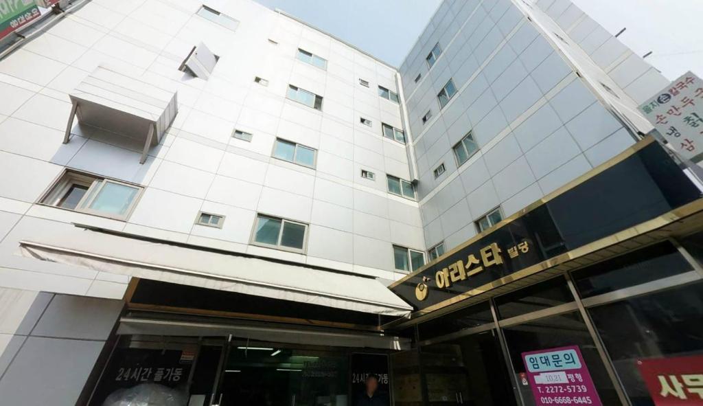 - un grand bâtiment blanc avec un panneau devant dans l'établissement Tripstay Myeongdong, à Séoul