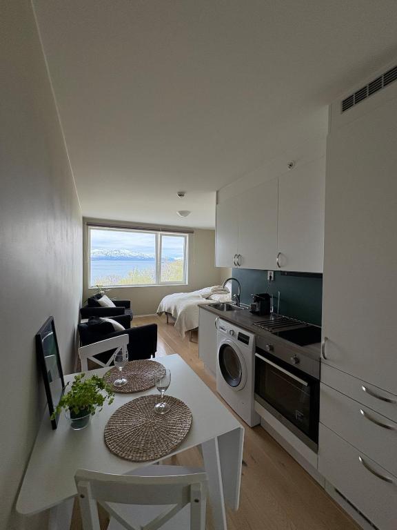 a kitchen and living room with a table and a dining room at Cozy Apartment in Tromsø