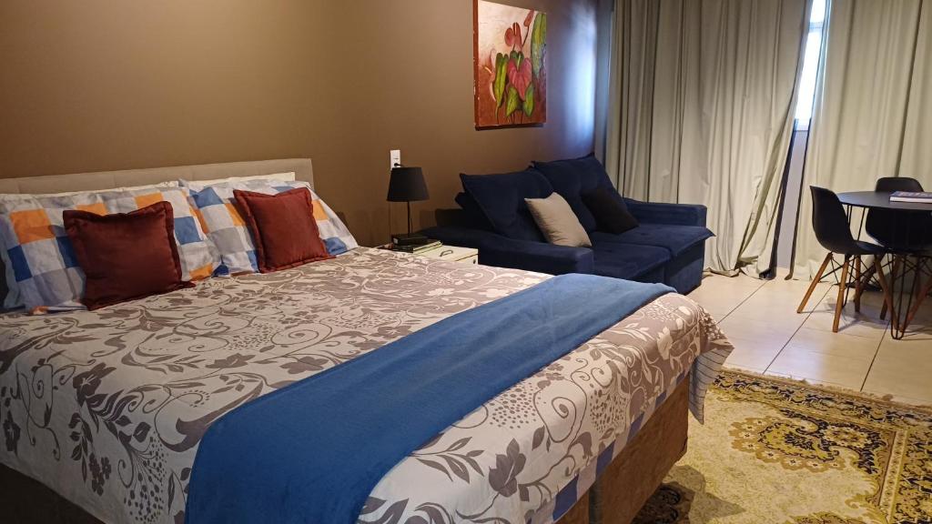 a bedroom with a large bed and a blue couch at Studio Barreto Leme Ap72 in Campinas