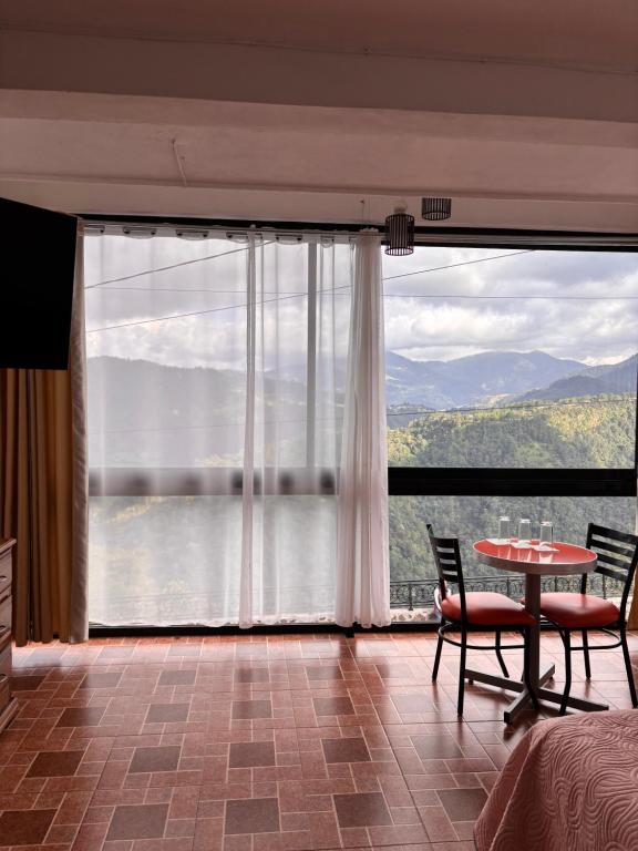 een kamer met een tafel en stoelen en een groot raam bij Hotel la barranca 5 in Zacatlán