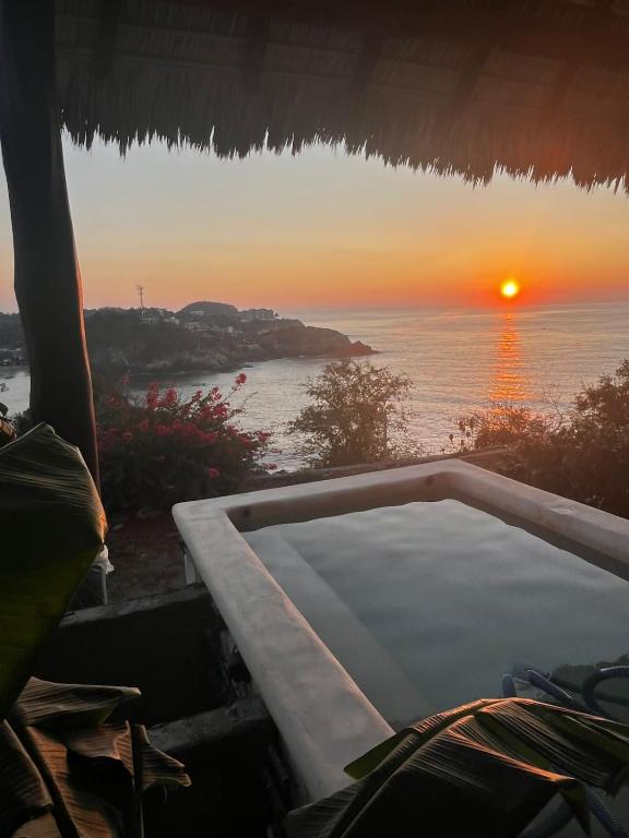 a bath tub with a view of the ocean at sunset at Angelita's Nest House in Puerto Ángel