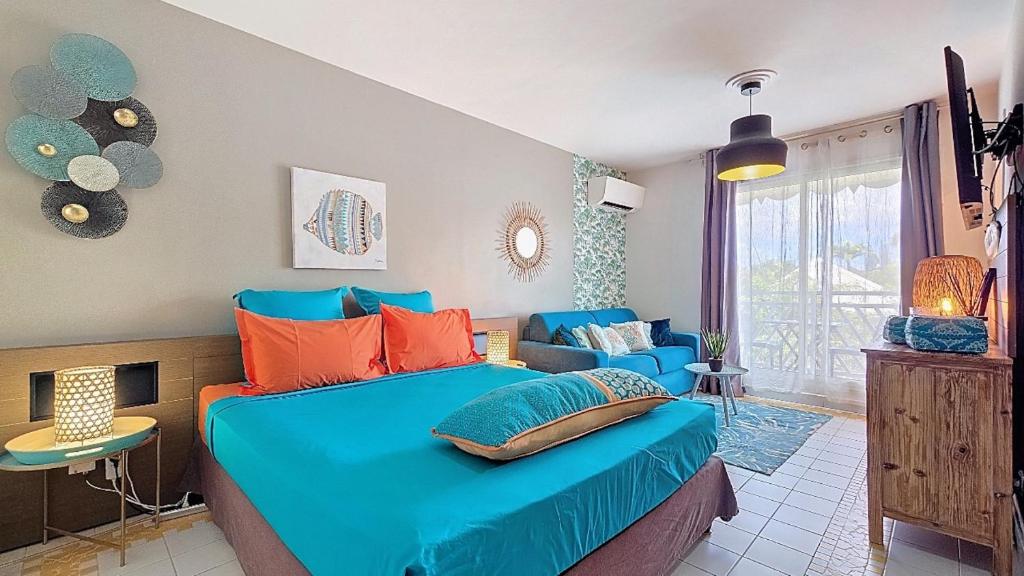 a bedroom with a blue bed and a couch at PARADISIAC LAGOON in Saint-François