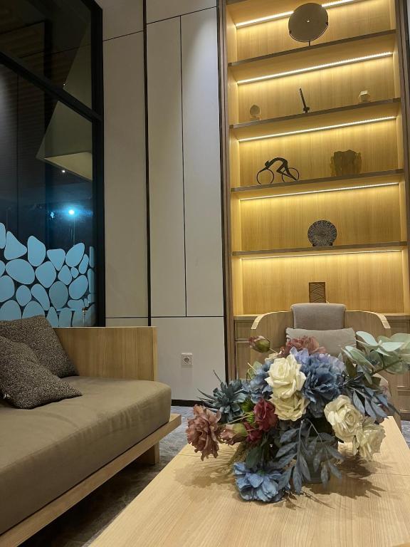 a living room with a couch and a table with flowers at Osaka riverview Apartment PIK 2 by SS in Rawalumpang
