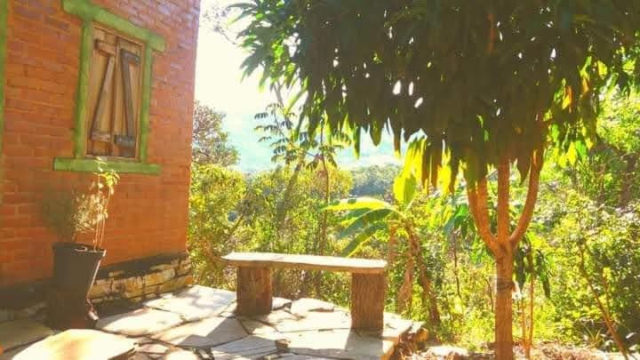 a table and a tree in front of a building at Winará - Turismo de aventura in São Thomé das Letras