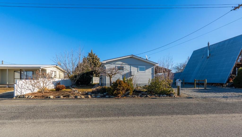 a house with a blue building next to a street at Modernised Mackenzie with central location. in Twizel