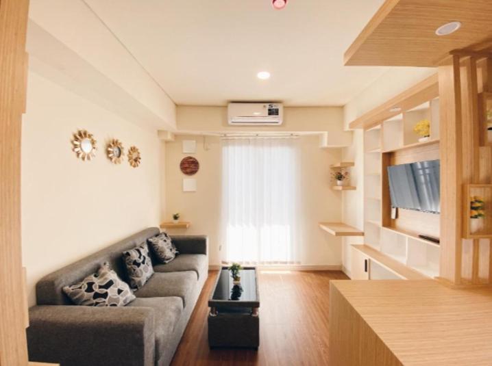 a living room with a couch and a flat screen tv at Sweety rooms Apartemen meikarta distrik 1 in Tegaldanas
